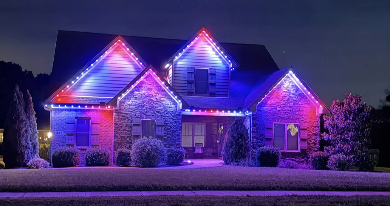 Stone and brick home with permanent holiday roofline lighting at night
